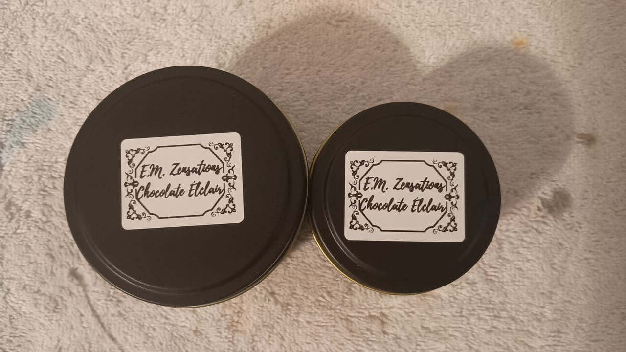 Chocolate Éclair Candle packaging in round black containers with decorative labels.