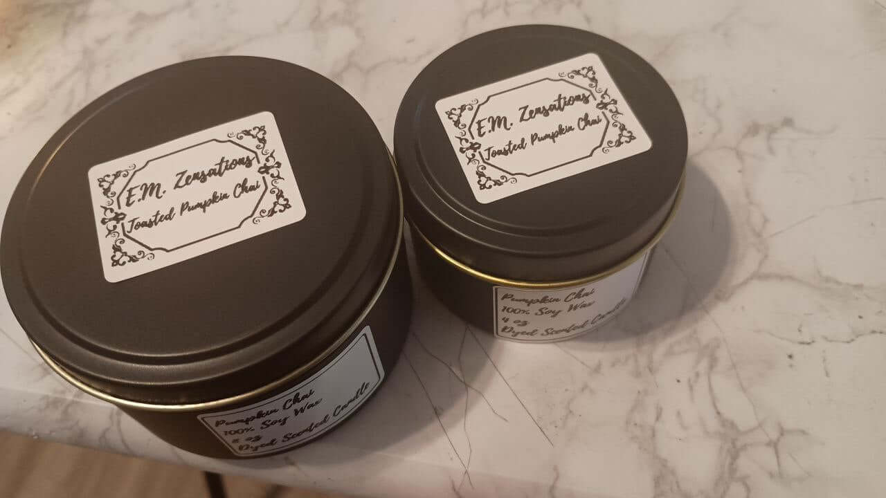 Toasted Pumpkin Chai Candle in two stylish metal tins on a marble surface.