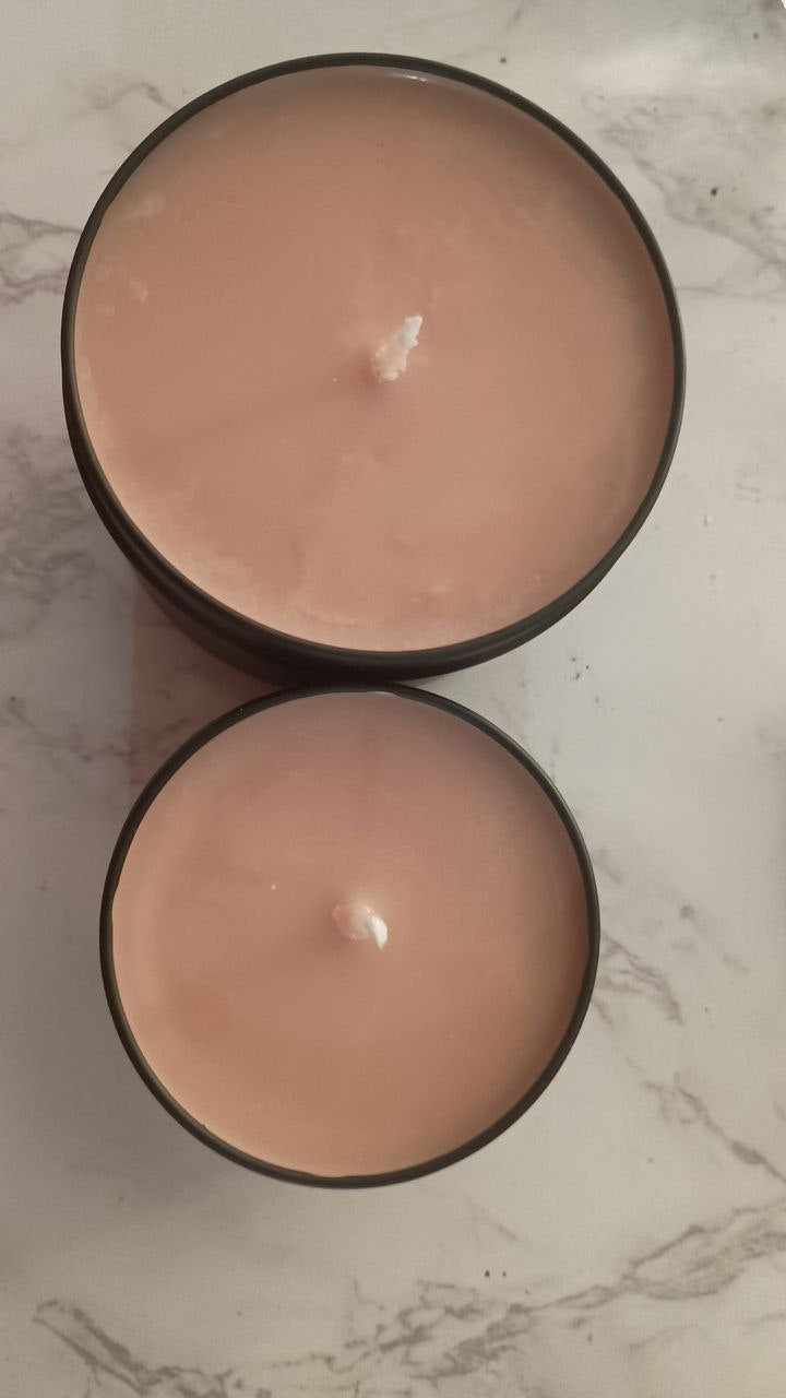 Two round pink candles of different sizes on a marble surface, showcasing their smooth tops.