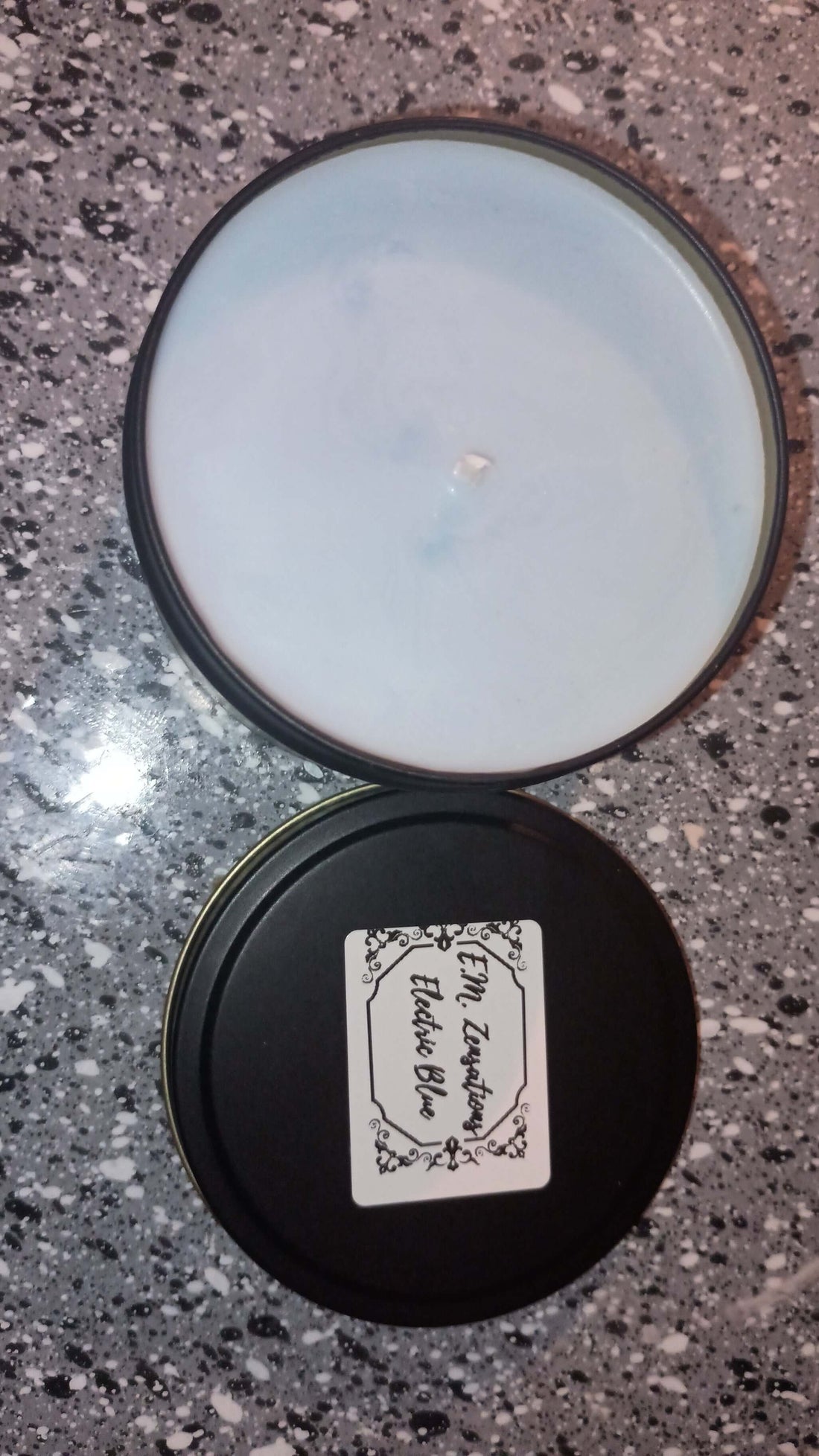 Electric Blue Scented Candles in a black tin, featuring a fresh blue wax and label on a granite surface.